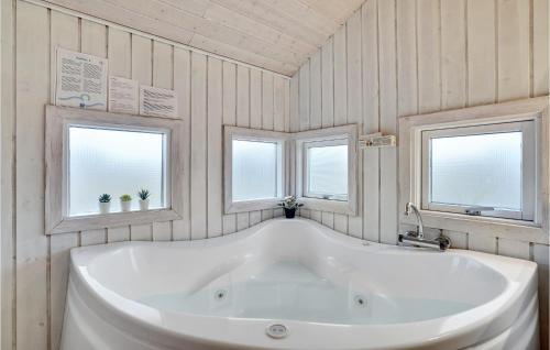 uma grande banheira branca numa casa de banho com 2 janelas em 3 Bedroom Stunning Home In Hvide Sande em Bjerregård