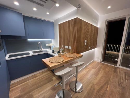 una cocina con armarios azules y una isla de madera con taburetes en SeaJewelsDeluxurySuite, en Amalfi