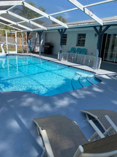 a large swimming pool with chairs and an umbrella at Pool house near beach in West Melbourne