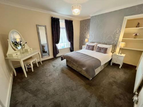 een slaapkamer met een bed, een bureau en een spiegel bij Scoresby Quarters - Whitby Holiday Home in Whitby