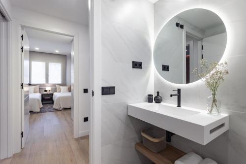 a white bathroom with a sink and a mirror at ApartsNouBcn Equador Les Corts in Barcelona