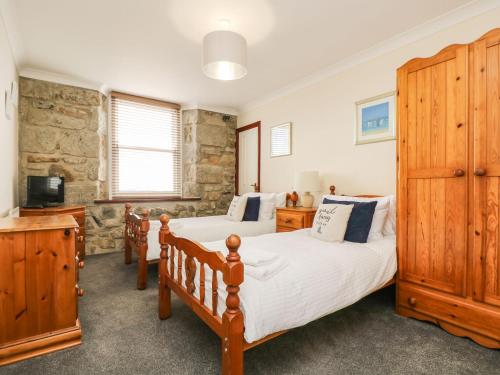 彭贊斯的住宿－Jubilee Cottage，一间卧室设有两张单人床和一台电视机。