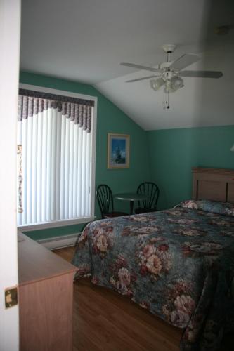 a bedroom with a bed and a ceiling fan at Escale de l'île - Auberge Janine du Havre in Shippagan