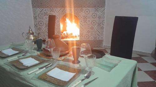 a table with a green table cloth with a fireplace at Riad SARSAR airport in Marrakech