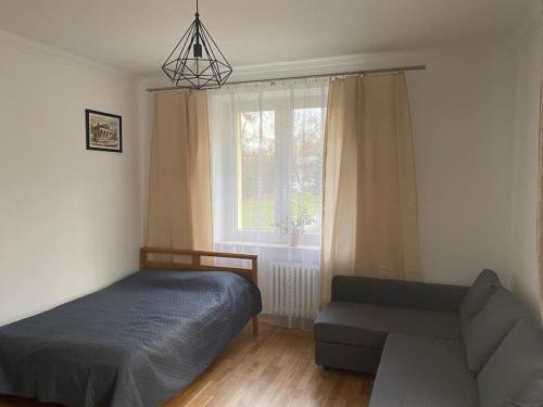um quarto com uma cama, um sofá e uma janela em Apartament przy Parku Czartoryskich II em Puławy