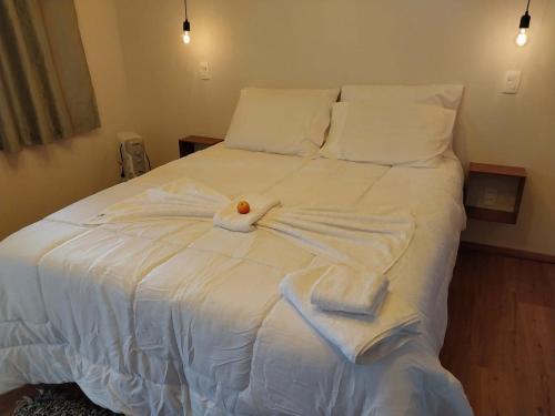 a white bed with towels on top of it at Chalé dos Pellizzari in Monte Verde