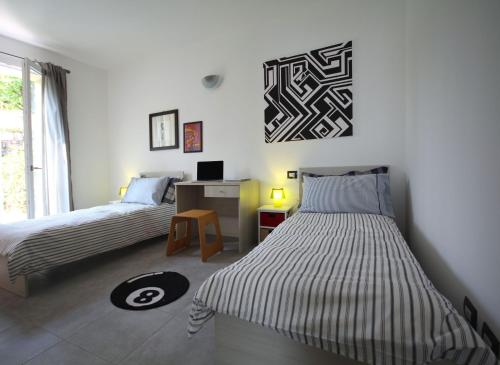 a bedroom with two beds and a desk and a window at Via Volta Lenno in Tremezzo