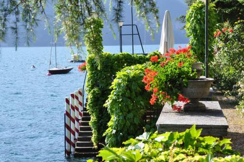 a garden with flowers and a boat in the water at Villa Angela Maria - Brienno by LoveComo in Brienno
