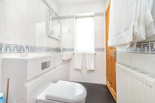 La salle de bains blanche est pourvue de toilettes et d'une fenêtre. dans l'établissement Journeyman Loft, à Skipton