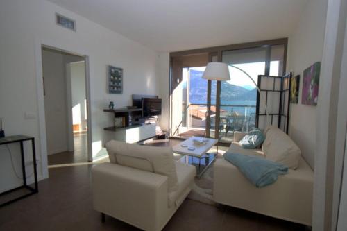 a living room with two white chairs and a table at Vista Panorama Jewel - Acquaseria, San Siro by LoveComo in San Siro