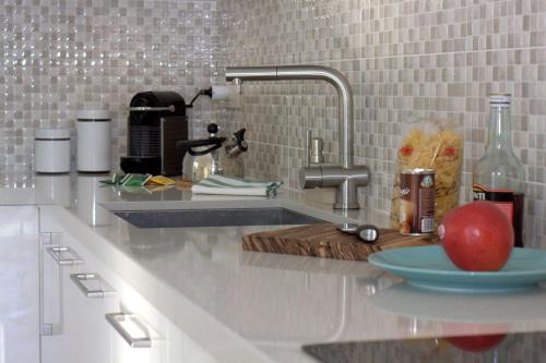 a kitchen counter with a sink and an apple on a plate at Vista Panorama Jewel - Acquaseria, San Siro by LoveComo in San Siro