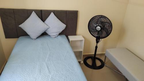 a bedroom with a bed with a fan next to it at Casa de Temporada Aconchego in Macaé