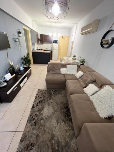 a living room with a brown couch and a kitchen at Carisa Holiday rooms in Larnaka