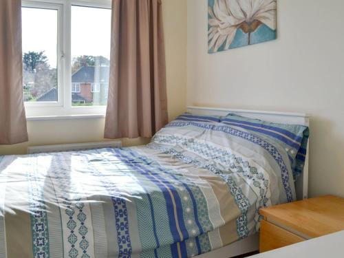 a small bedroom with a bed with a window at Beach House in Sheringham