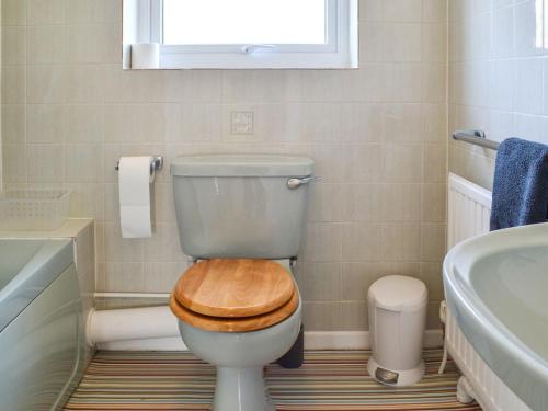 a bathroom with a toilet with a wooden seat at Beach House in Sheringham