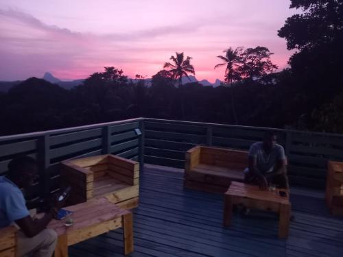 a couple of people sitting on a deck at sunset at Casa Cantagalo - Guest House & Bar Restaurant in SantʼAna