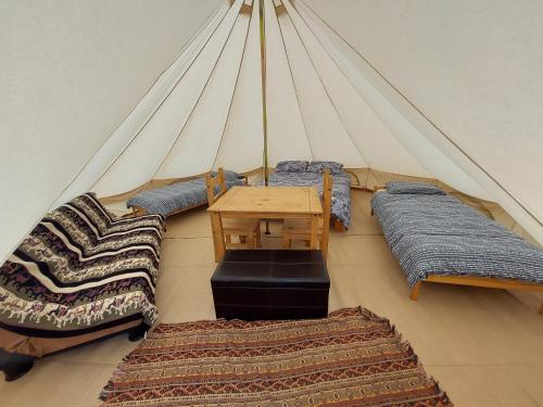 Tienda con 4 camas, mesa y 3 alfombras en The Meadows Bell Tents, en Clare