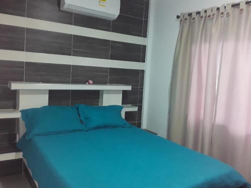 1 dormitorio con cama azul y pared en HOSTAL KASHI KAI, en San Juan del Cesar