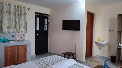 1 dormitorio con cama, lavabo y puerta negra en Marvel Studio Kitengela Yukos, en Kitengela 