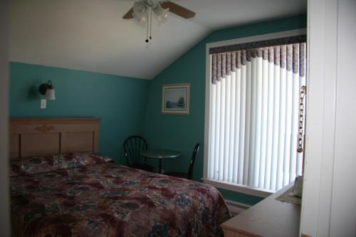 a bedroom with a bed and a window at Escale de l'île - Auberge Janine du Havre in Shippagan