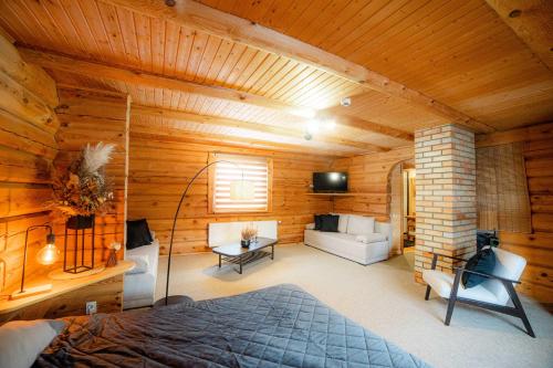 ein Schlafzimmer in einem Blockhaus mit einem Bett und einem Sofa in der Unterkunft Viesu nams SAKNĪTES in Dzērbene