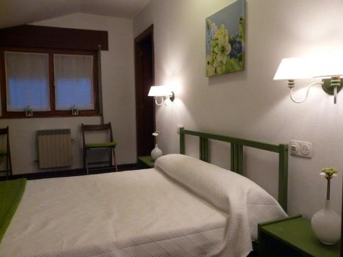 een slaapkamer met een bed, 2 lampen en een raam bij Casa Vasca in Llanes