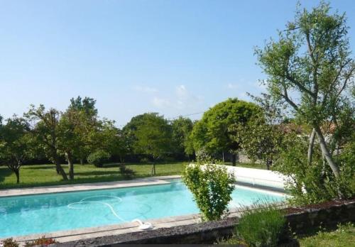 a swimming pool in a yard with trees at Gîte Au Petit Bonheur in Saint-Savinien