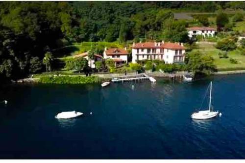 zwei Boote im Wasser vor einem Haus in der Unterkunft Villa Giardino con pontile sul Lago D’Orta in riva in Orta San Giulio