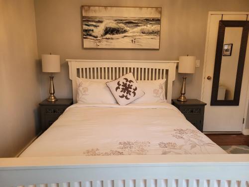 a bedroom with a white bed with two lamps at Campbell Cottage B&B in Nanaimo