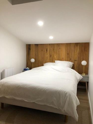 - une chambre dotée d'un grand lit blanc avec des boiseries dans l'établissement Duplex neuf, 15mn de Paris, parking, climatisation, à Bourg-la-Reine