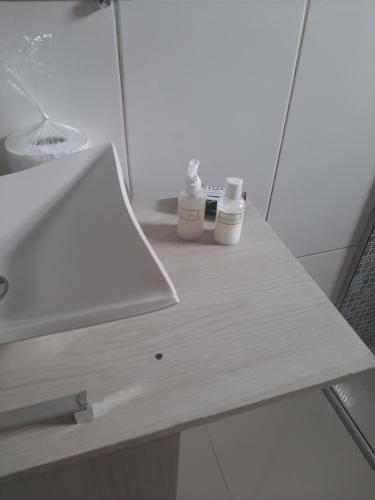 Un mostrador de baño con lavabo y dos botellas. en Vista da Guarita en Torres