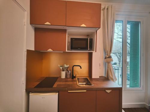 une cuisine avec un évier et un micro-ondes dans l'établissement Le Chic, à Ivry-sur-Seine