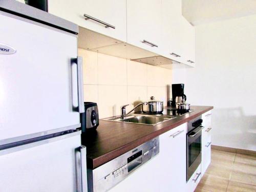 a white kitchen with a sink and a refrigerator at Villa Unique in Willemstad