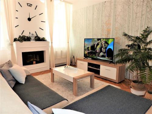エゲルにあるLéna Apartman - Egerのリビングルーム(ソファ、テレビ、時計付)