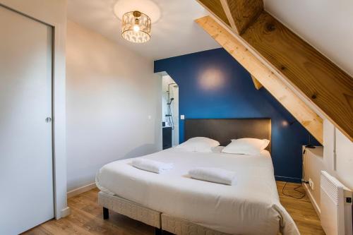 a bedroom with a large bed with a blue wall at Maison vélo piscine tennis in Deauville