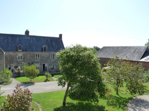 een oud huis met een boom ervoor bij Gîte Utah du DOMAINE DE SAINT-VIGOR 