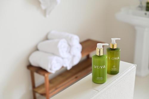 two green bottles of towels on a shelf with a chair at Russells Cottage in Doolin