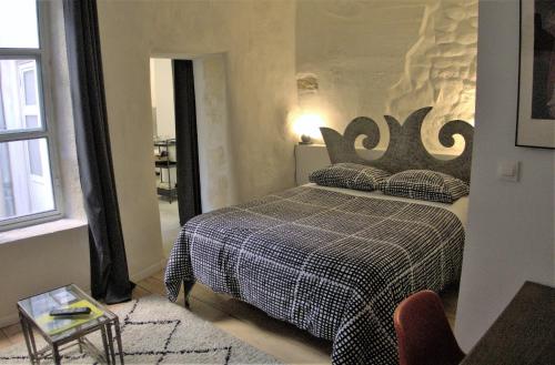 a bedroom with a bed with a black and white blanket at Ô Anges in Arles