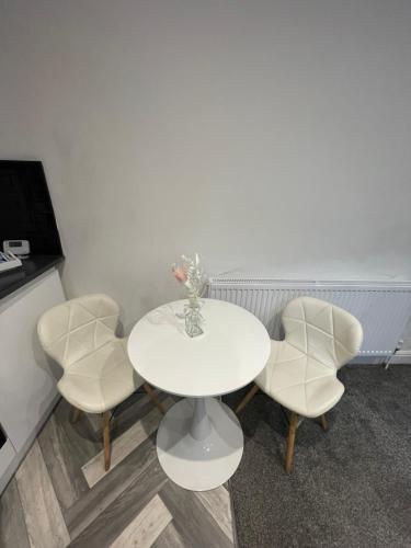 Modern Spacious 2 Bedroom Apt في Rowley Regis: طاولة بيضاء عليها اربعة كراسي و مزهرية