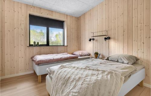 Duas camas num quarto com paredes de madeira e uma janela em Pet Friendly Home In Hadsund With Sauna em Hadsund