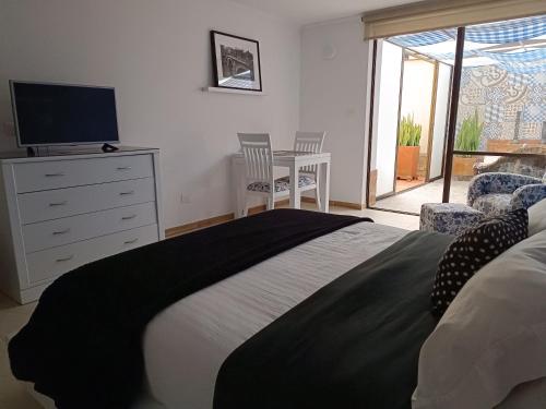 a bedroom with a bed with a dresser and a television at Hotel Boutique Confort Suites in Popayan