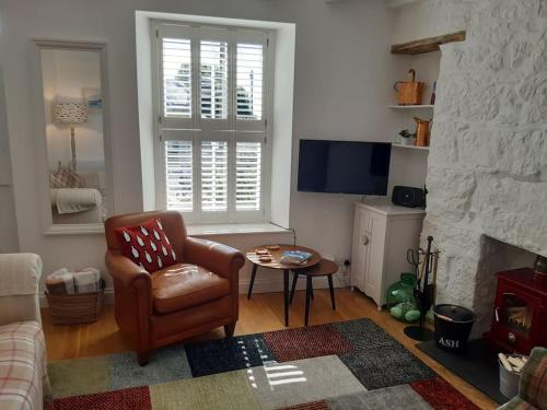 ein Wohnzimmer mit einem Stuhl und einem Kamin in der Unterkunft Corvus - Beautiful cottage half a mile from Mousehole in Penzance