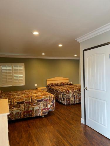 two beds in a room with wooden floors at El Rey Inn - LAX in Gardena