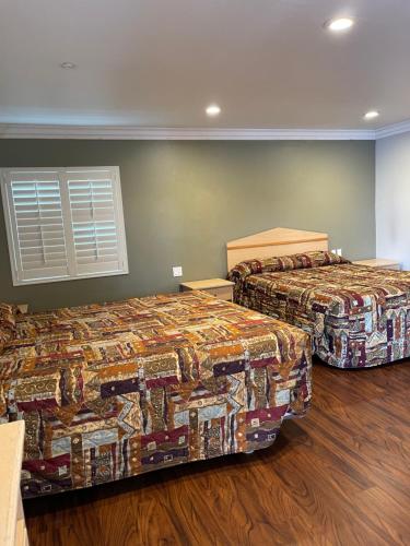 Duas camas num quarto com pisos em madeira em El Rey Inn em Gardena