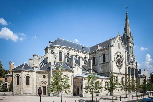 un gran edificio con una iglesia con una torre de reloj en Chambre équipée (proche Paris), en Argenteuil