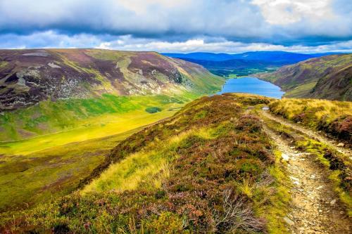 a road on the side of a hill with a lake at Golden Eagle Lodge in Kingussie