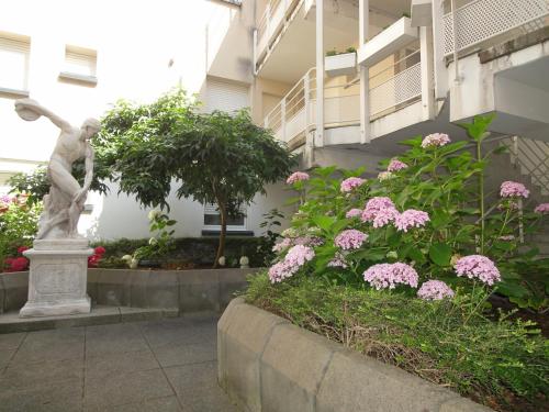 une statue en face d'un jardin avec des fleurs roses dans l'établissement Kosly garden Robertsau, à Strasbourg