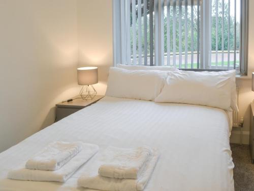 a bedroom with a white bed with two towels on it at Forest Close in Forest Hall