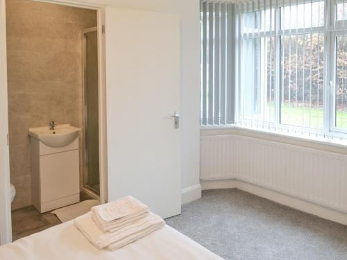 łazienka z łóżkiem, umywalką i oknem w obiekcie Forest Close w mieście Forest Hall