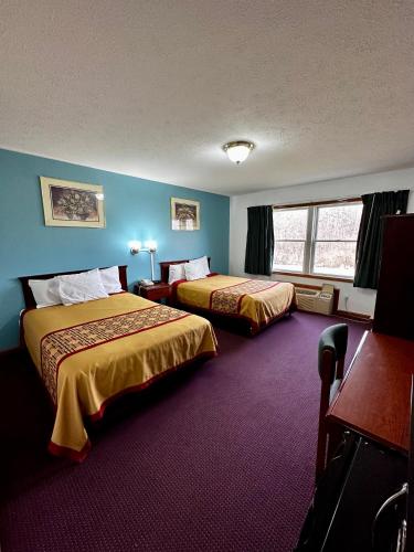 two beds in a hotel room with blue walls at Attica Inn in Attica